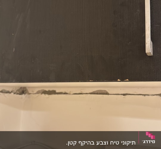 ארון מטבח עם ידיות מתכת וקיר עם תיקון טיח